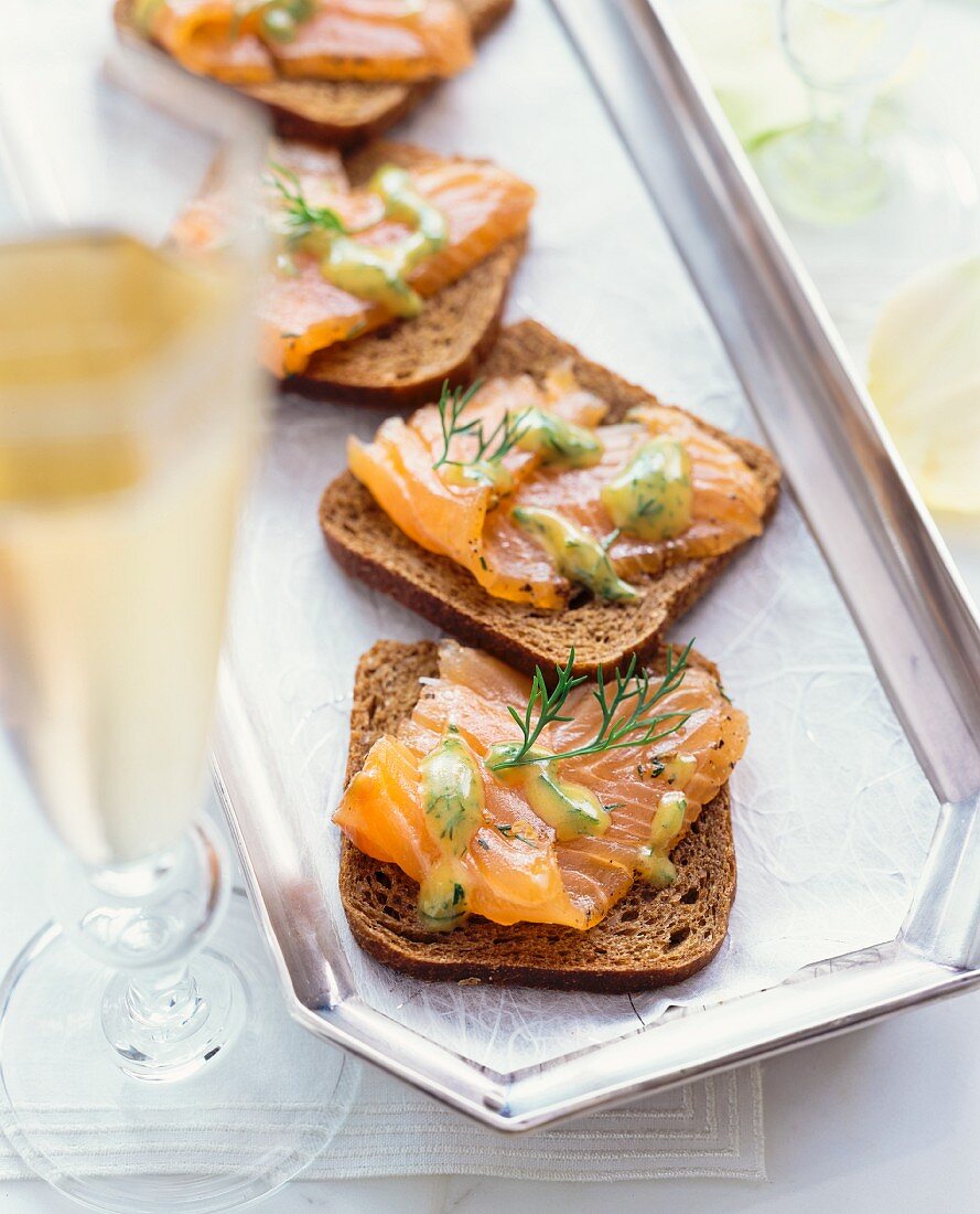 Slices of bread topped with smoked salmon and a dill sauce