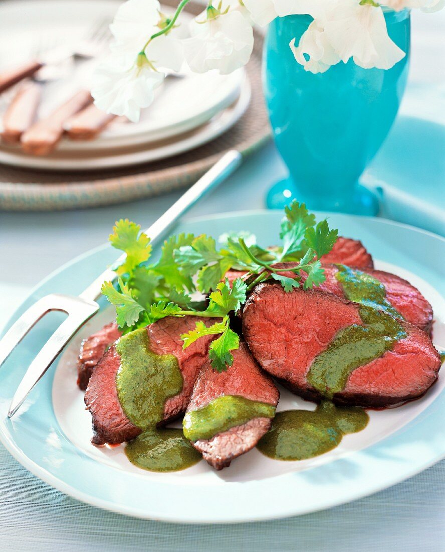 Slices of roast beef with a herb sauce and coriander