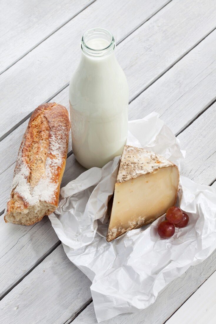 An arrangement featuring a bottle of milk, sheep's cheese and a baguette