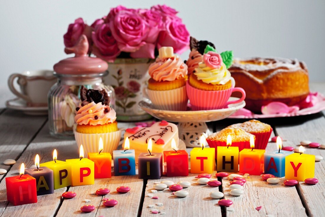 A colourful birthday buffet featuring cake and cupcakes