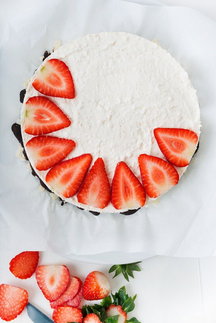 A creamy cheese cake being decorated with strawberries