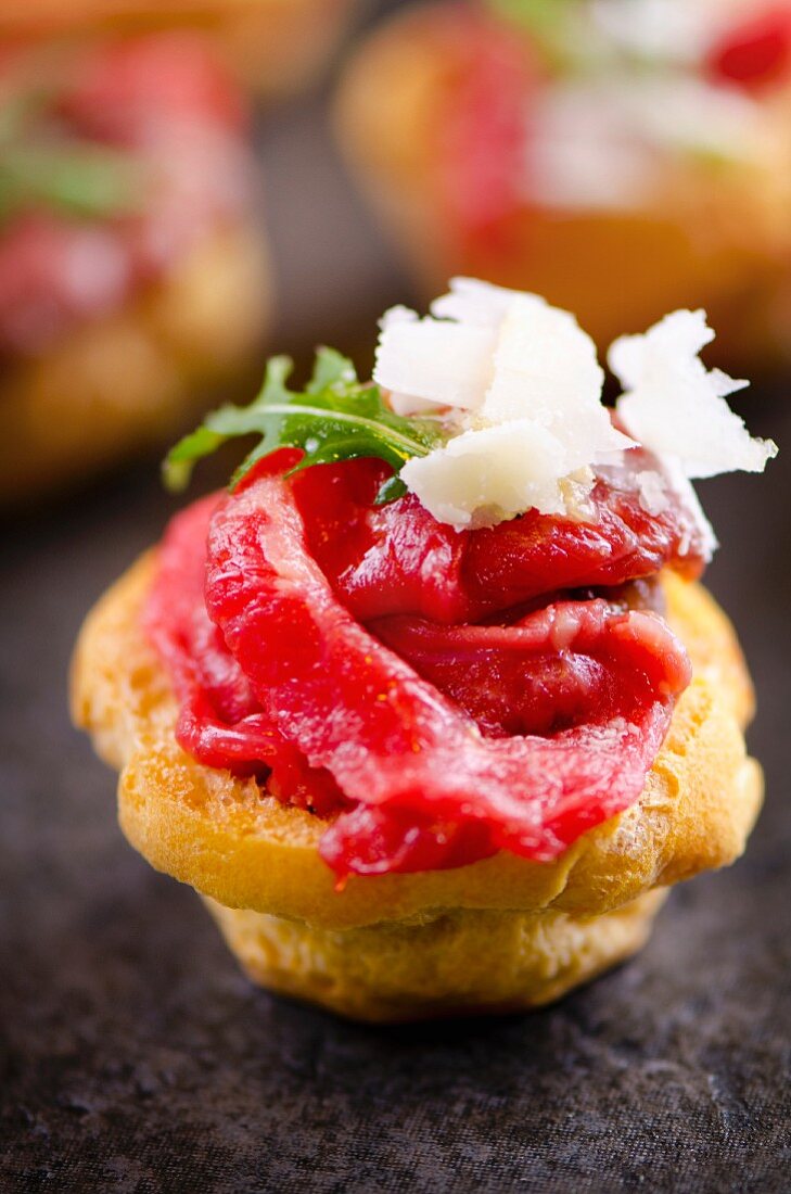 A profiterole with beef carpaccio, rocket and grated Parmesan