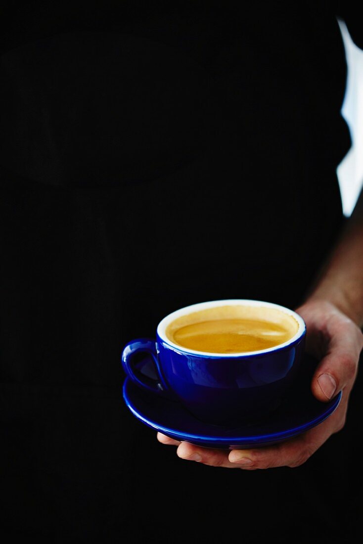 A barista holding an espresso