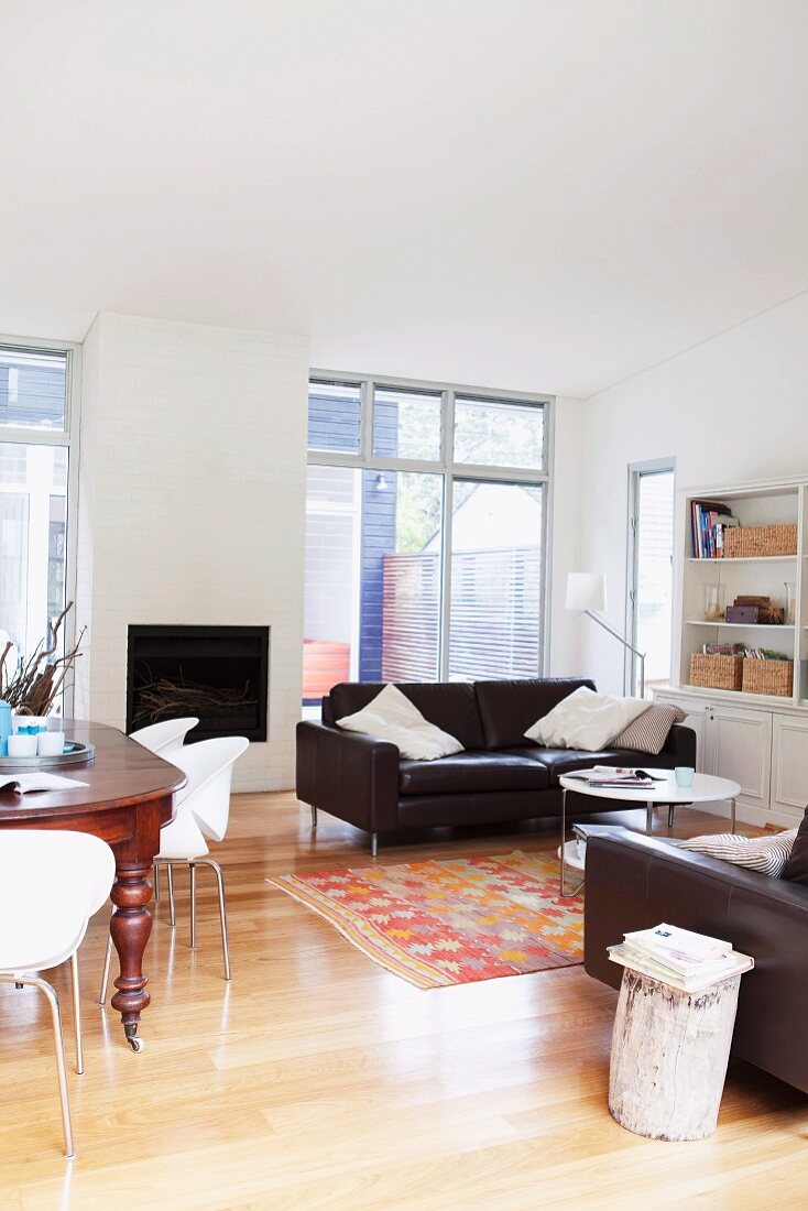 Elegant, open-plan interior with parquet floor and dark brown, leather sofa set