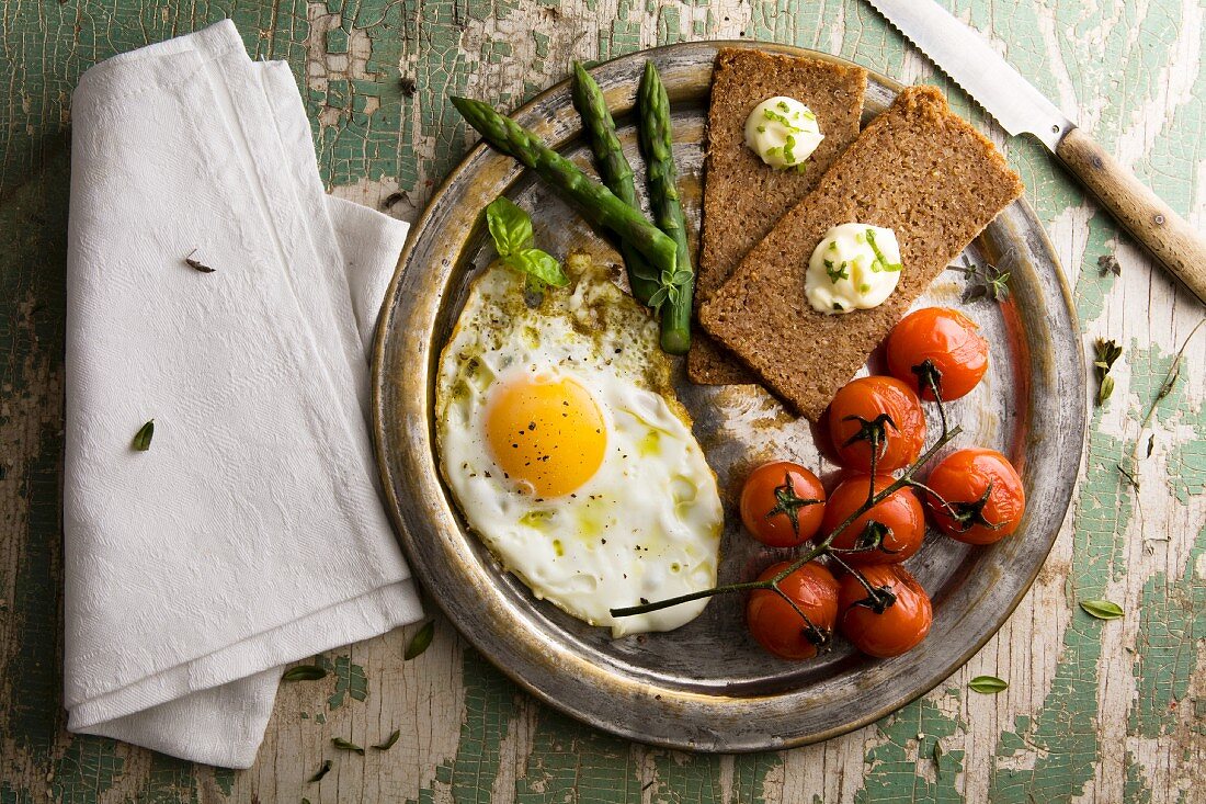 Fried egg with steamed tomatoes, asparagus and rye bread