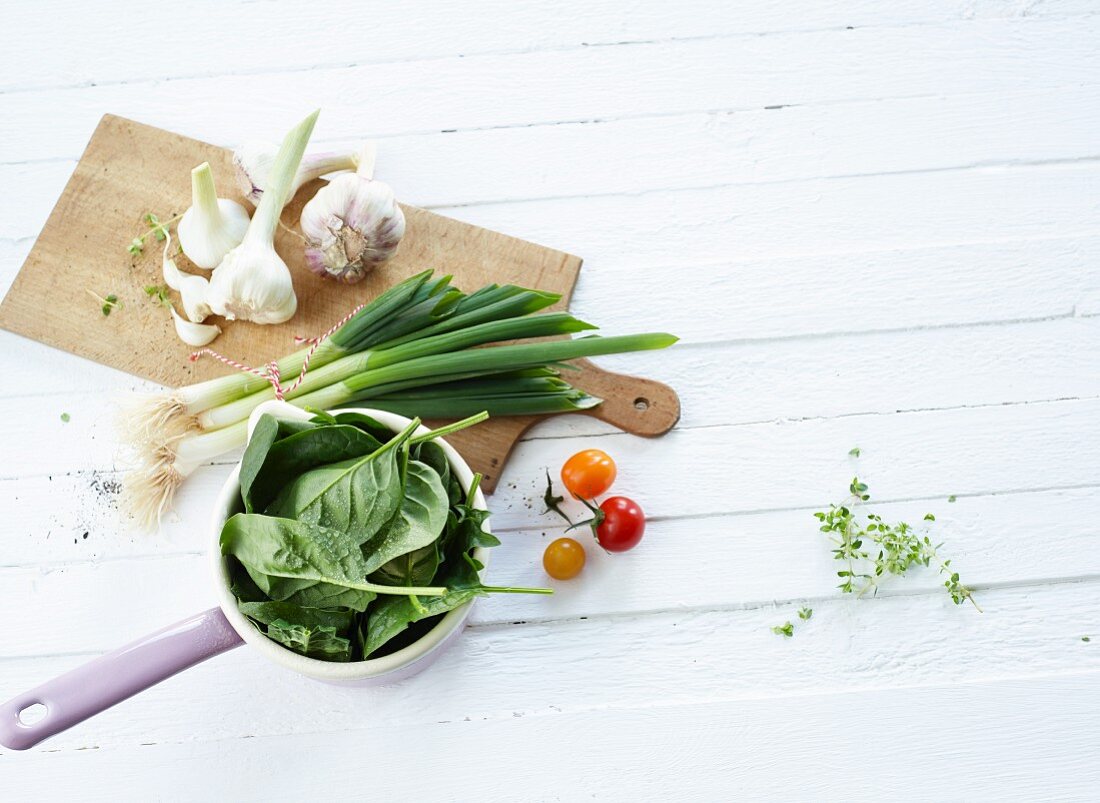 Gemüsestillleben mit Knoblauch, Spinat, Frühlingszwiebeln und Kirschtomaten