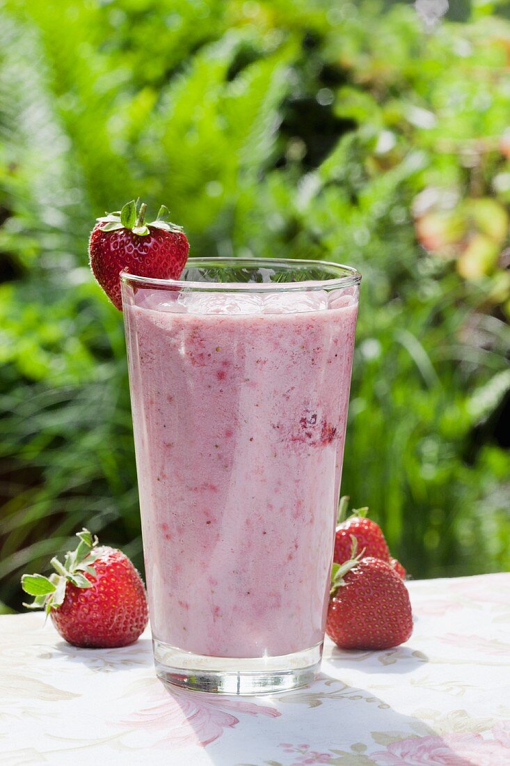 Erdbeersmoothie und Erdbeeren auf Gartentisch