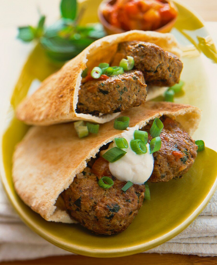 Meatballs in pita bread with spring onions and sour cream