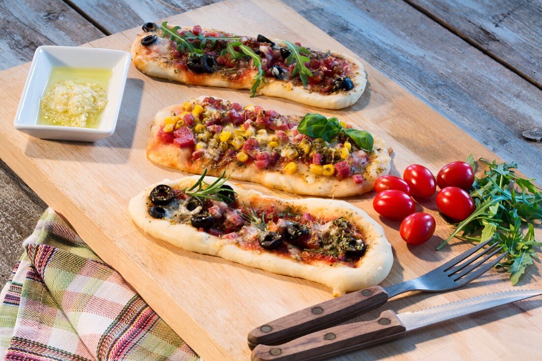 Pizza baguettes with ham, salami, mozzarella, tomato, rocket, sweetcorn and olives