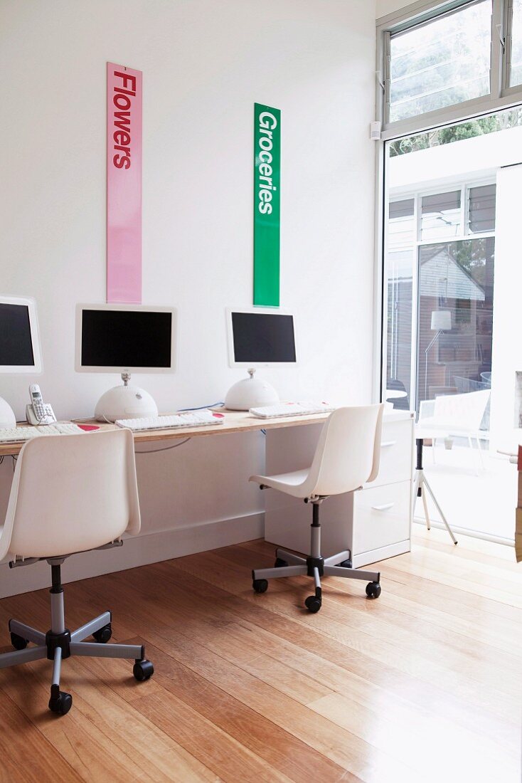 Modern, white home office with glass wall and parquet floor