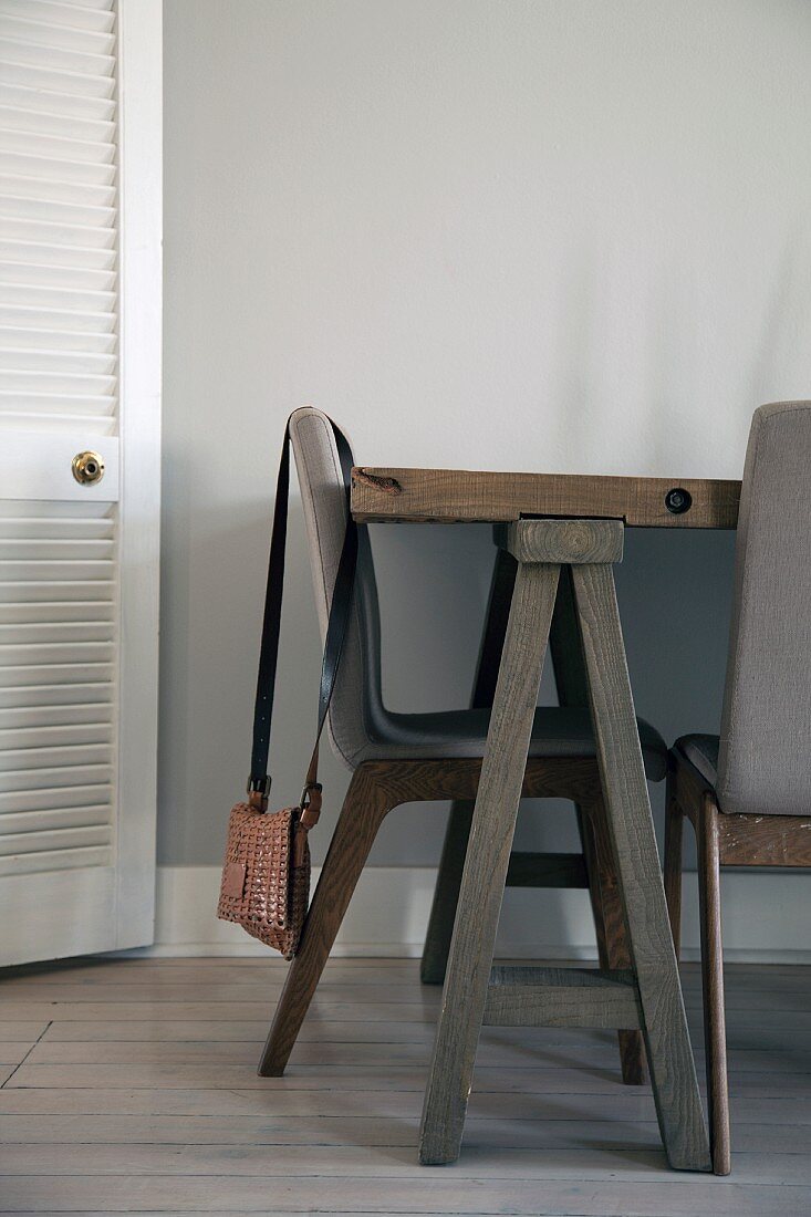 Dining area with upholstered chairs and rustic table on trestles; open slatted door to one side