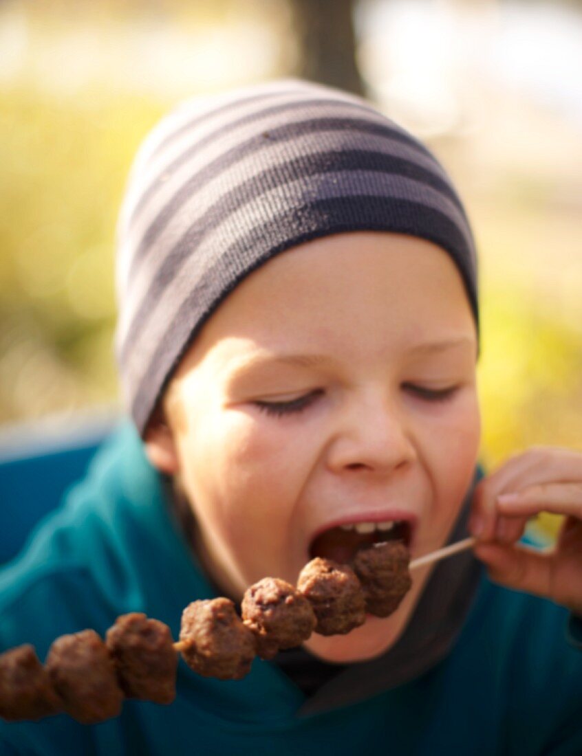 Kind isst Hackbällchenspiess beim Herbstpicknick