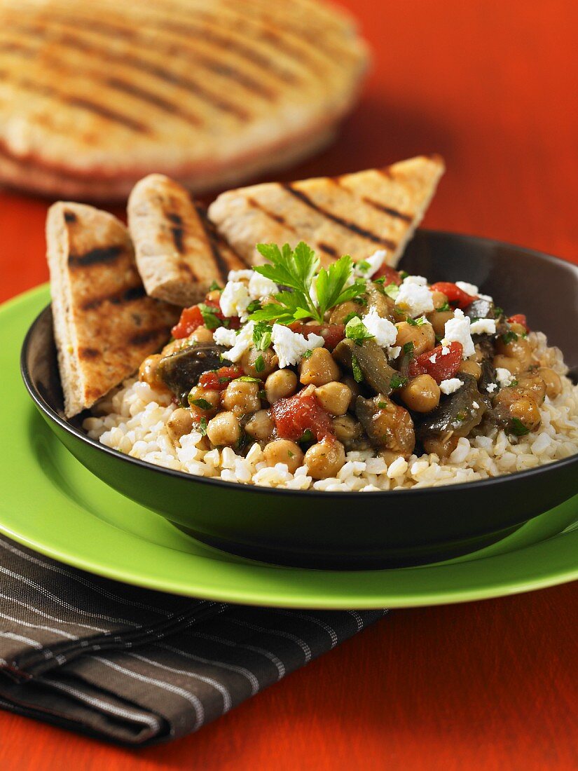 Mediterranean chickpea and vegetables stew on a bed of rice with toasted bread triangles