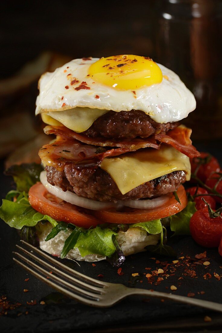 A cheese burger with bacon and a fried egg