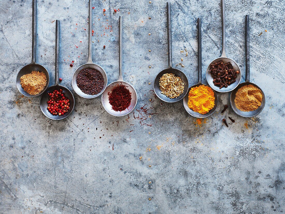 Spices in round spoons on a metal surface