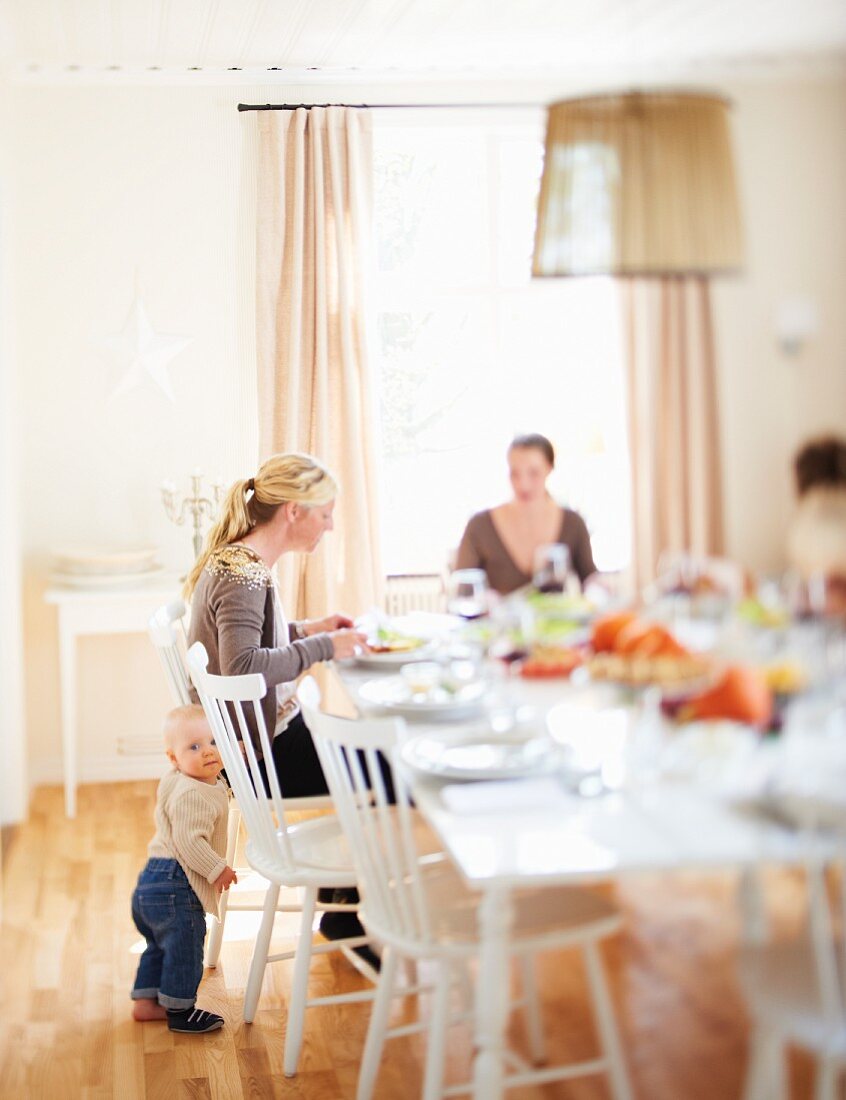 Two women and a small child at a table laid for Thanksgiving