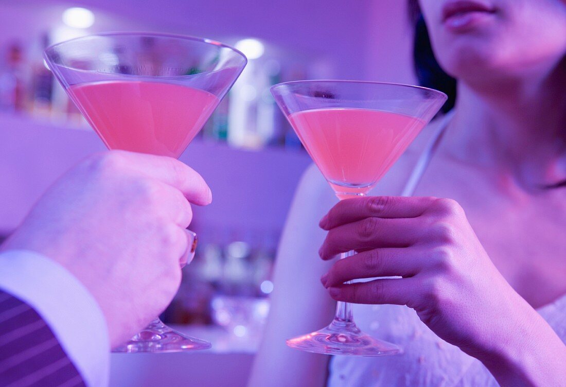 A man and a woman toasting with cocktails