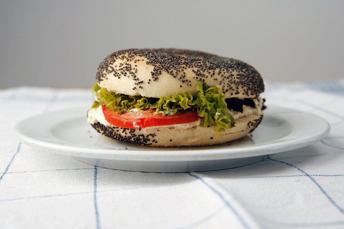 A sesame bagel with cream cheese, tomato and lettuce