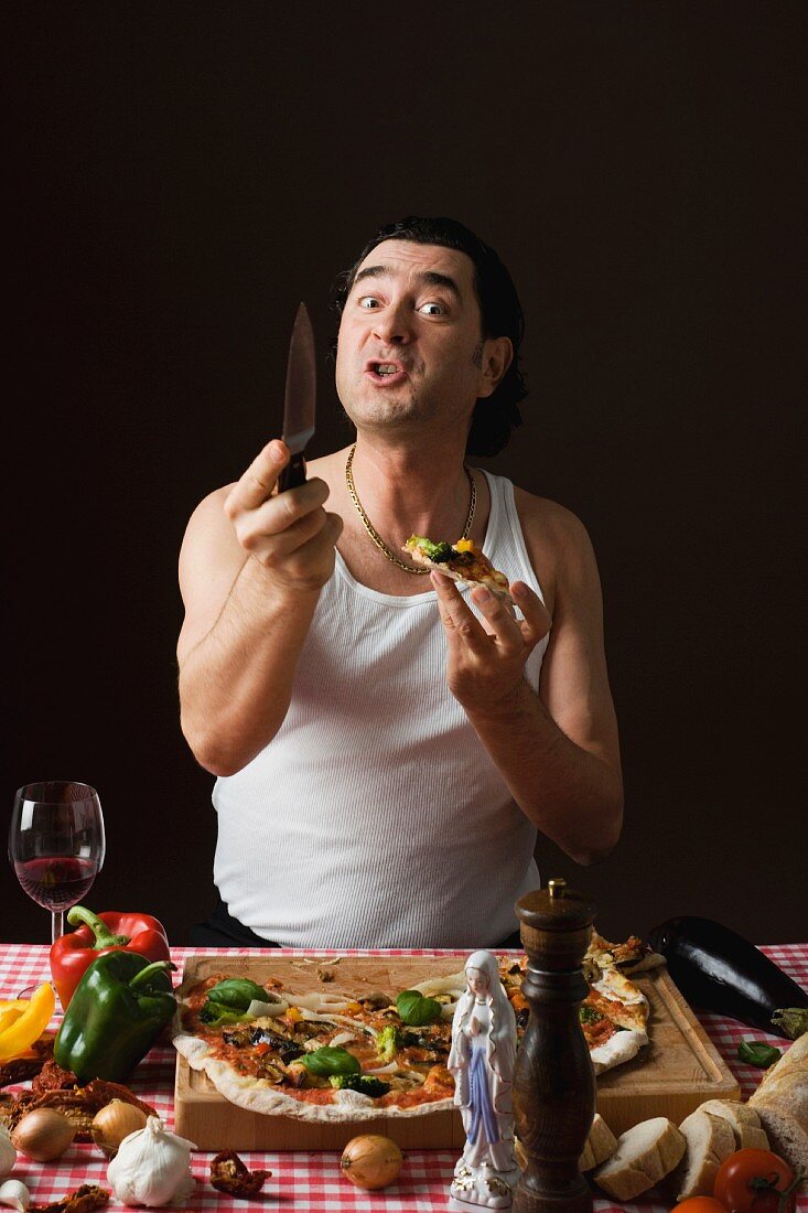 A stereotypical Italian man with a knife and a pizza