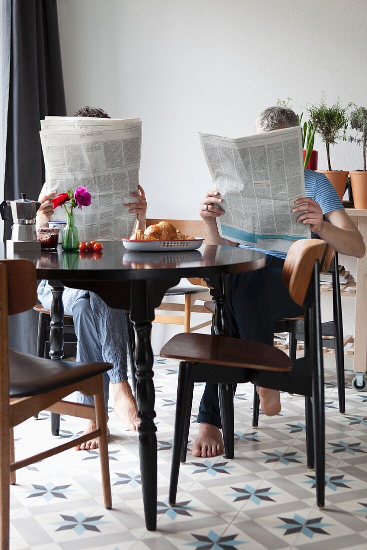 Paar liest Zeitung beim Frühstückstisch