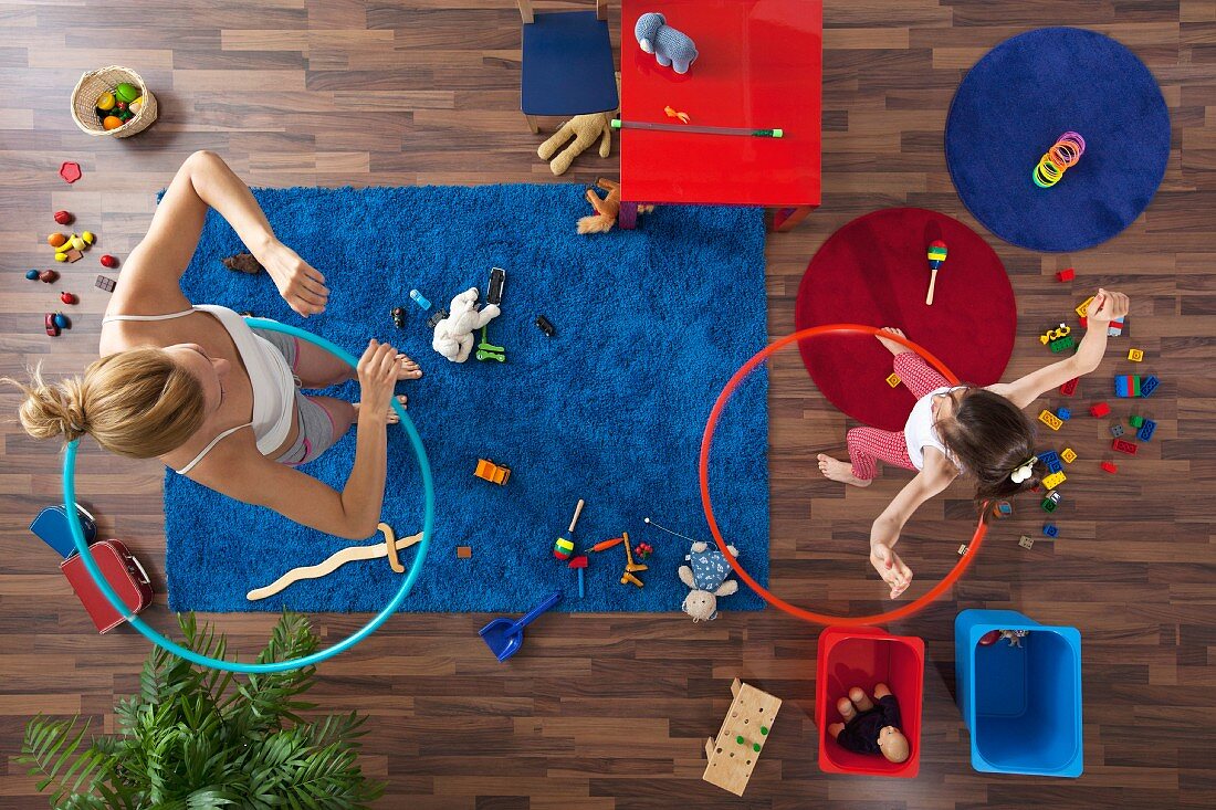 Mutter und Tochter mit Hula Hoop Ringen im Wohnzimmer