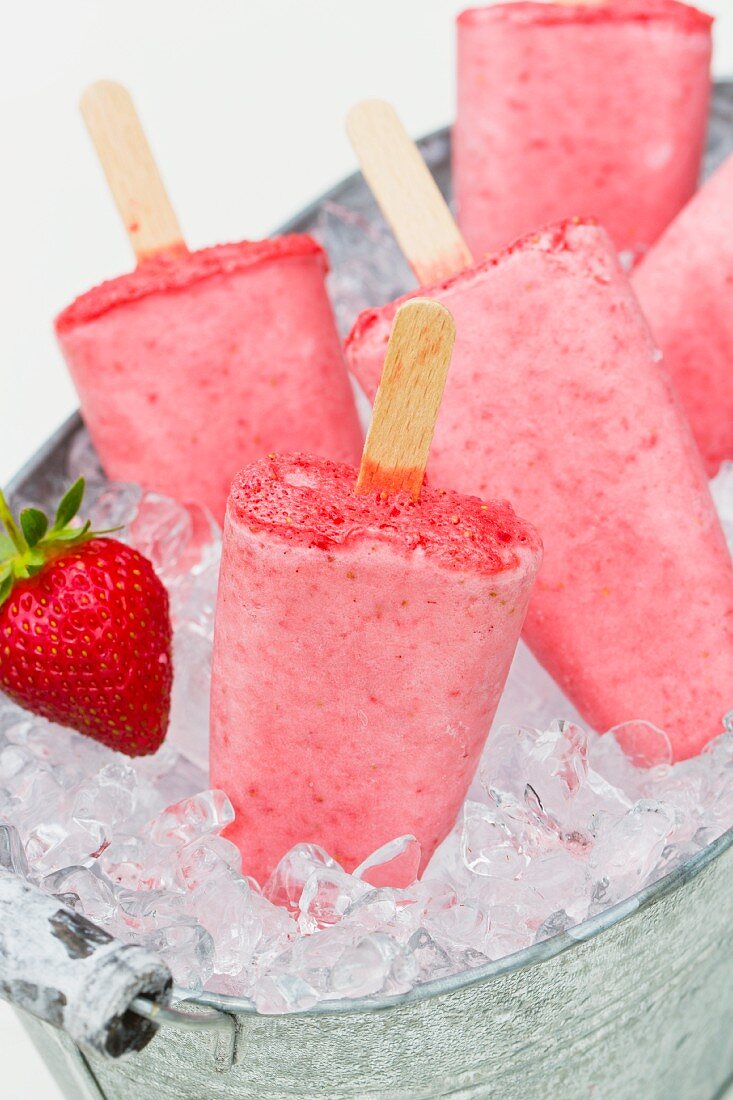 Strawberry ice cream sticks on crushed ice in a zinc tub