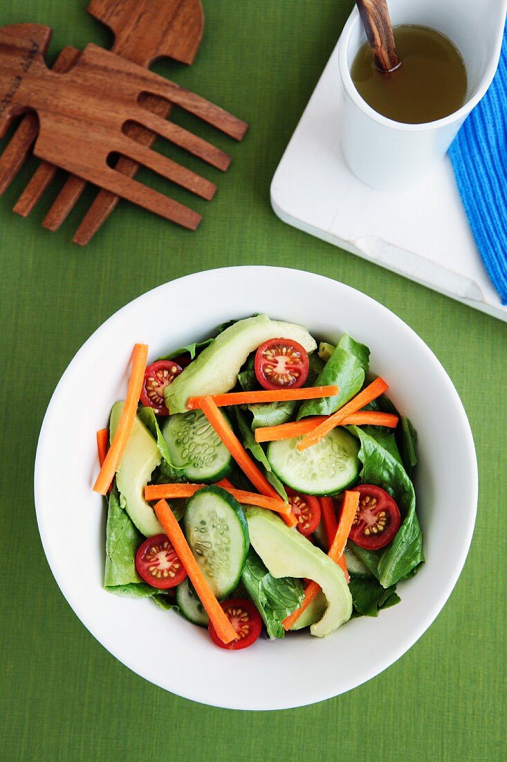 A garden salad with cucumber, avocado, carrots and cherry tomatoes