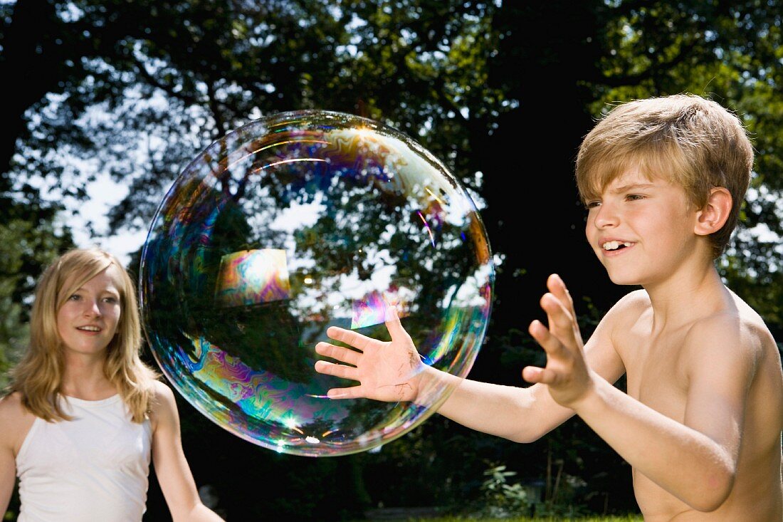 Zwei Kinder spielen mit Riesenseifenblase