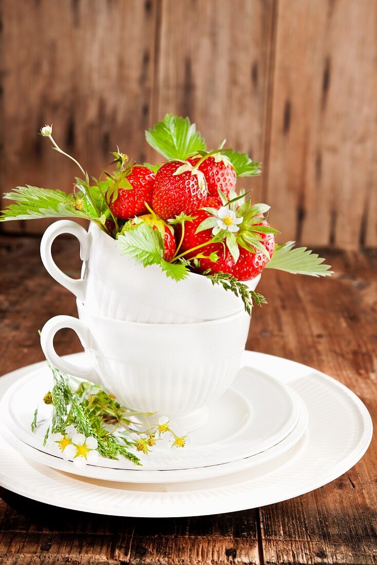 Strawberries with flowers and leaves in a cup