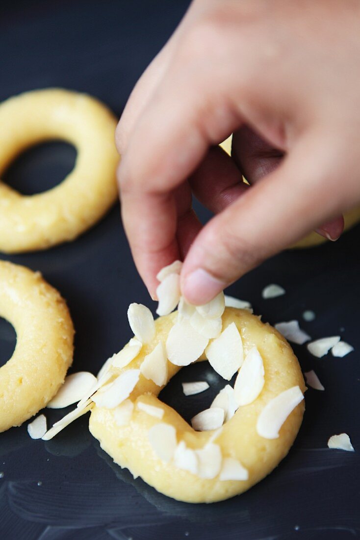 Choux pastry rings being sprinkled with slivered almonds