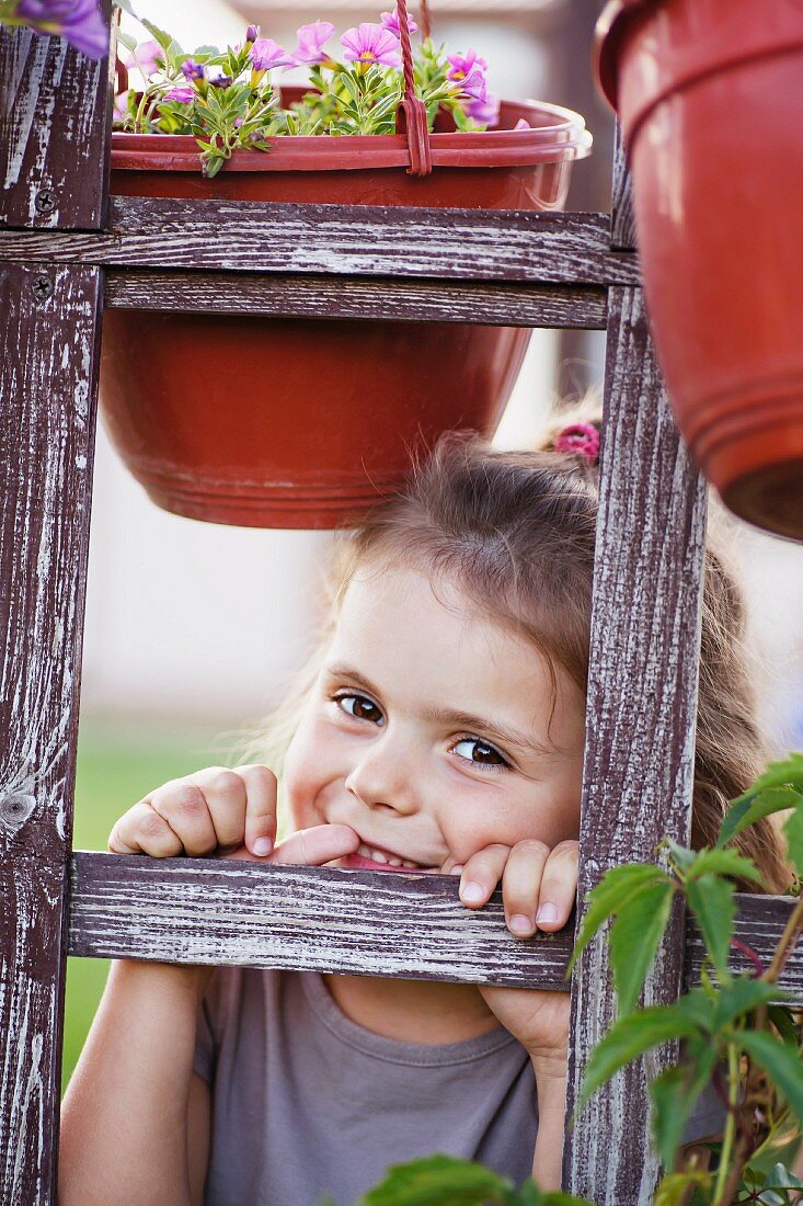 A young smiling girl looking through a trellis