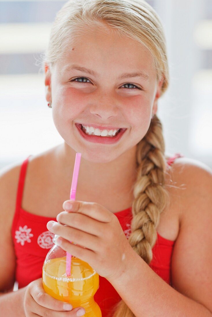 A smiling blond girl with orange juice