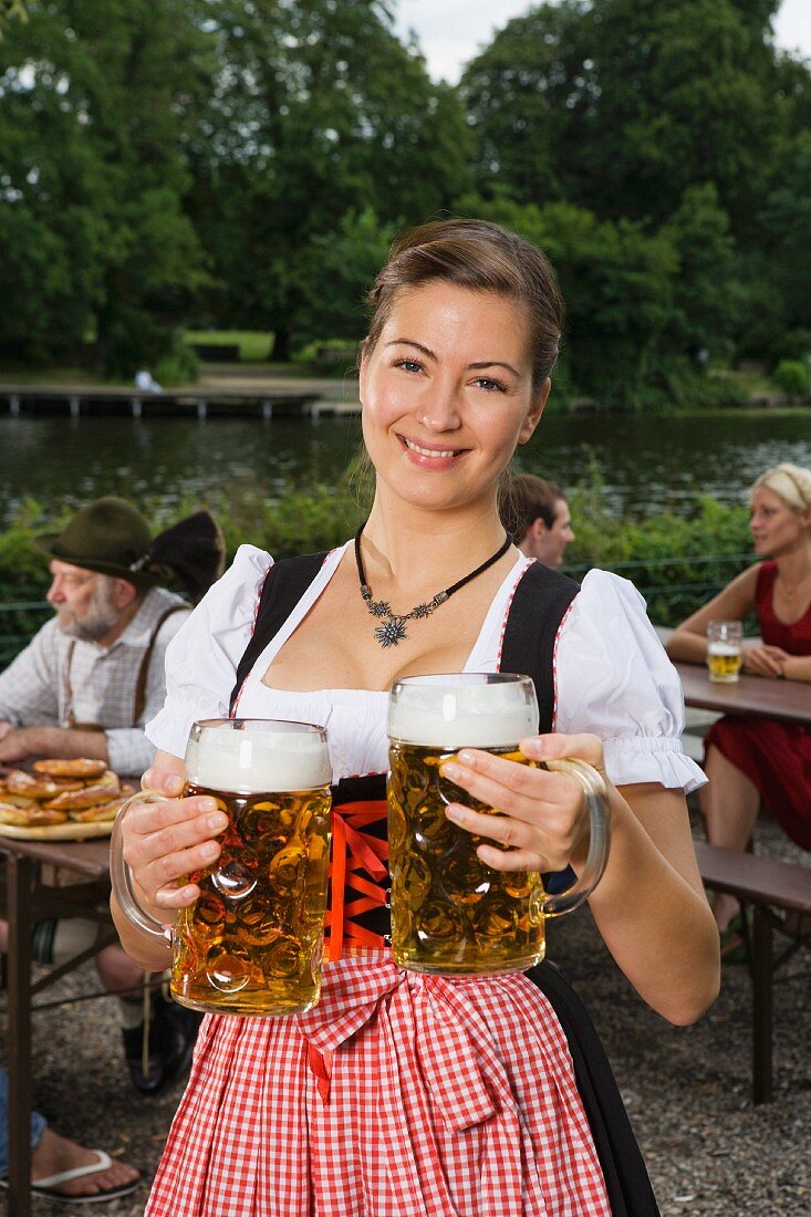 Bayerische Bedienung im Dirndl mit zwei Maßkrügen Bier