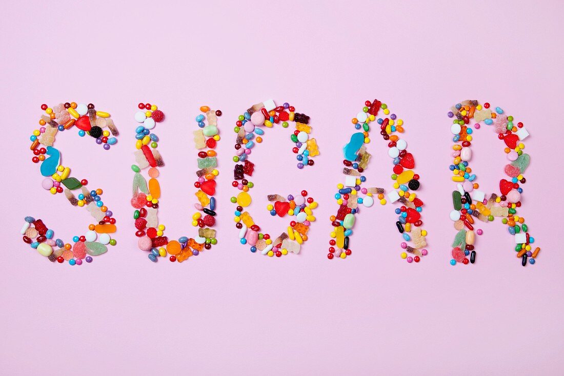 Das Wort SUGAR aus bunten Süßigkeiten gelegt
