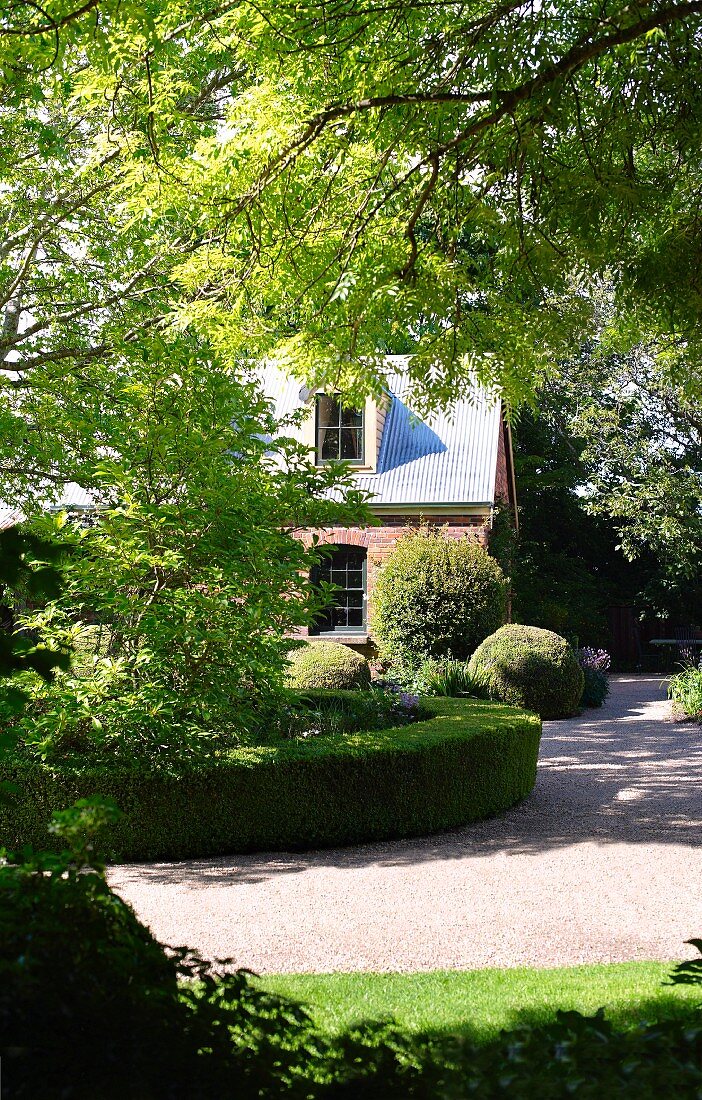 Summery garden with low hedges around flowerbeds in front of rural house