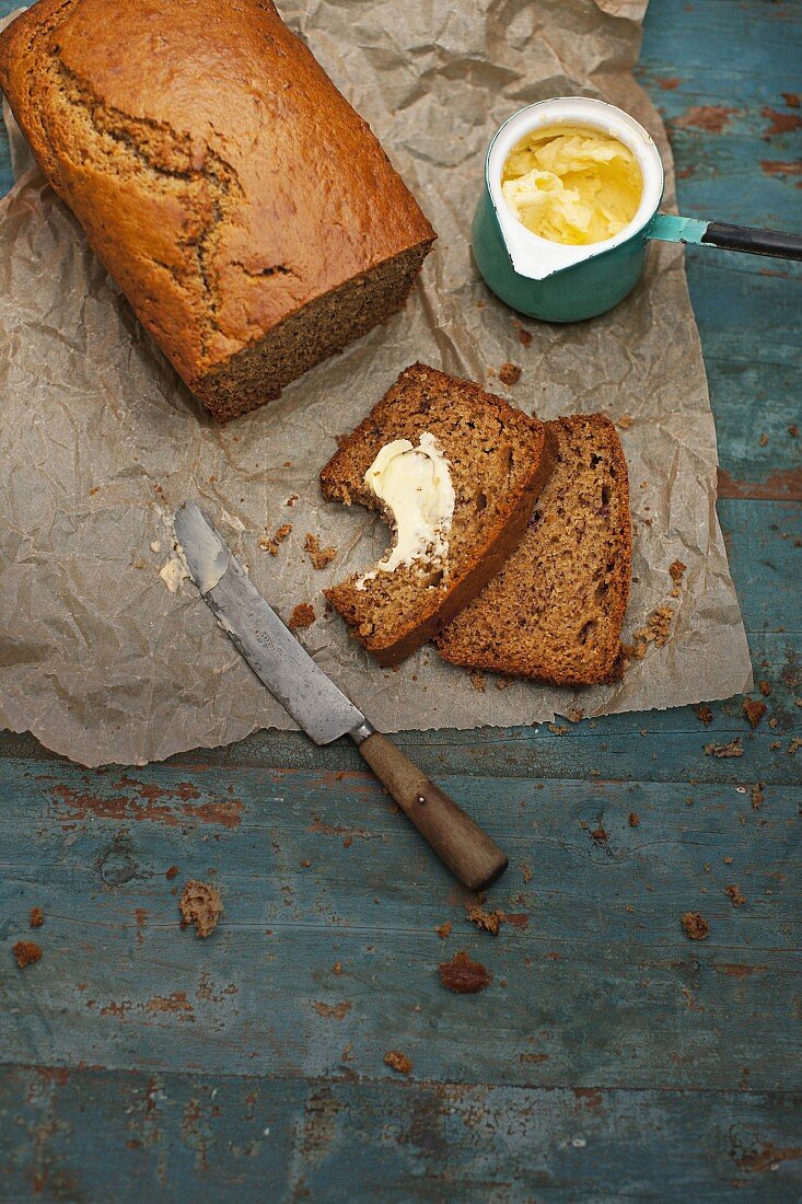 Sliced banana bread with maple syrup, one slice spread with butter