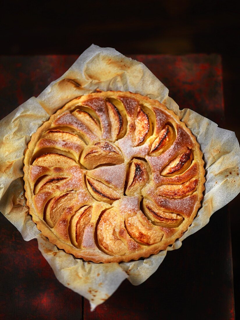 Apple tart with icing sugar on a piece of baking paper