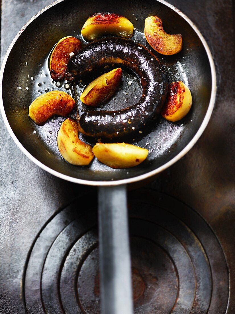 Fried blood sausage with apple wedges in a pan