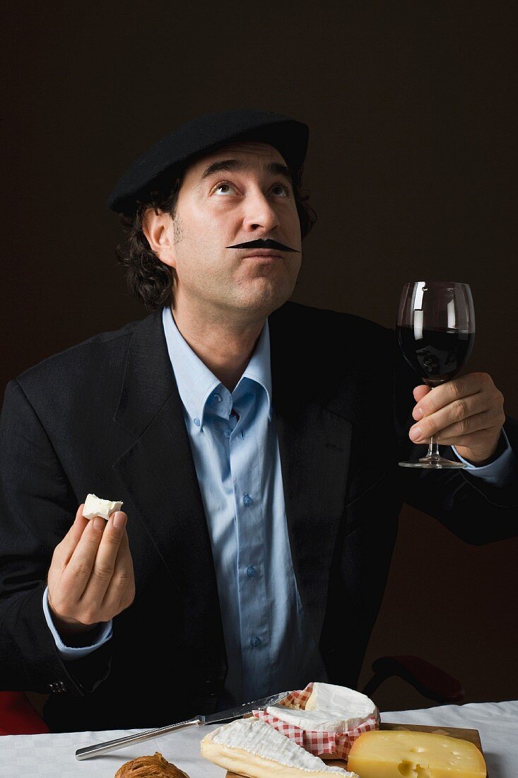 Typisch französischer Mann trinkt Rotwein zur Käseplatte