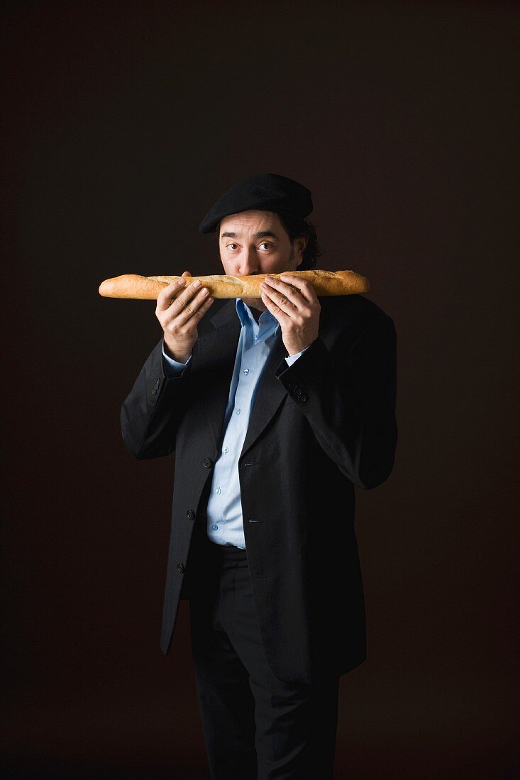 Typisch französischer Mann riecht an einem Baguette