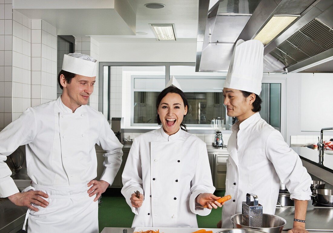 Three chefs joking around in a commercial kitchen