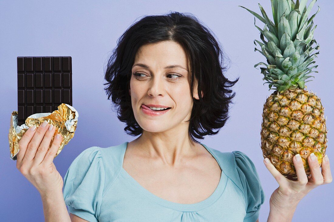 Frau hält Ananas und Schokoladentafel