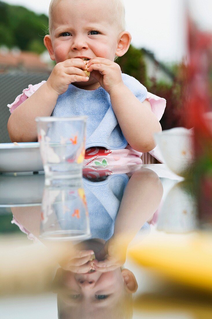 A toddler eating at a garden table