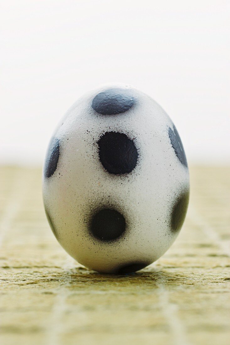 'Fußball-Ei' mit aufgesprühten schwarzen Tupfen