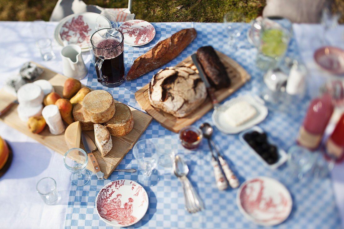 A cheese platter, bread and crockery on a garden table