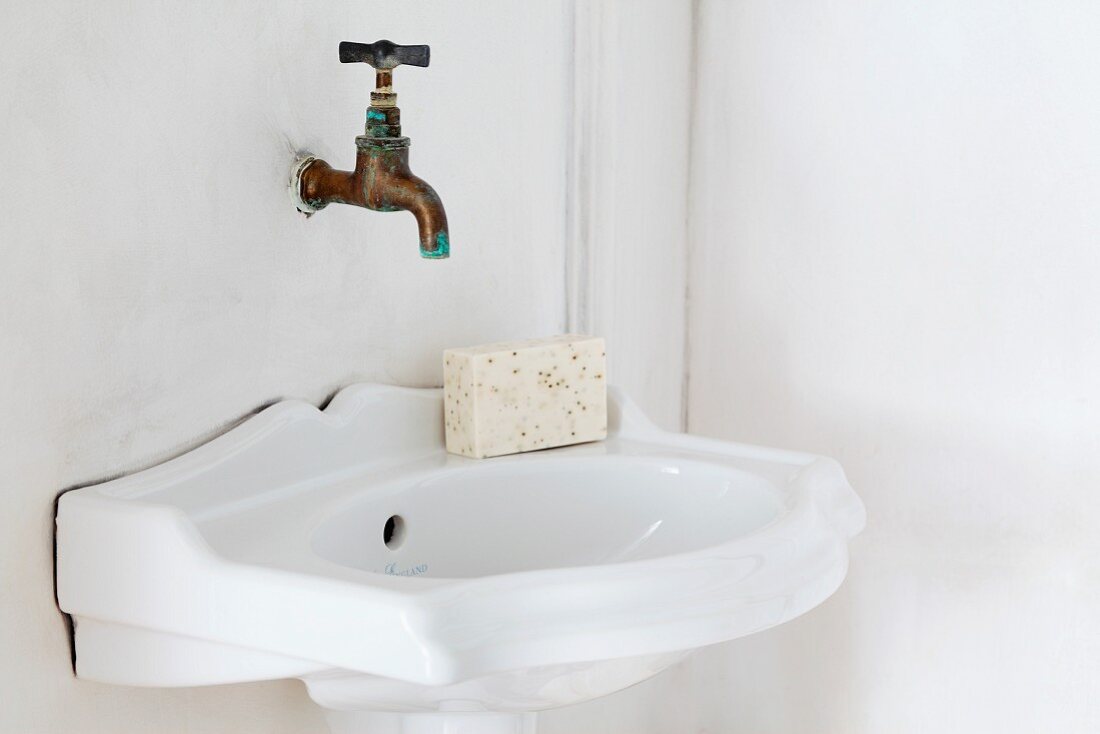 Vintage sink and wall-mounted copper tap in corner of bathroom