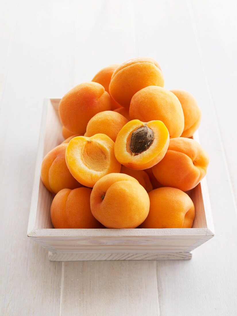 A pile of fresh apricots, one halved