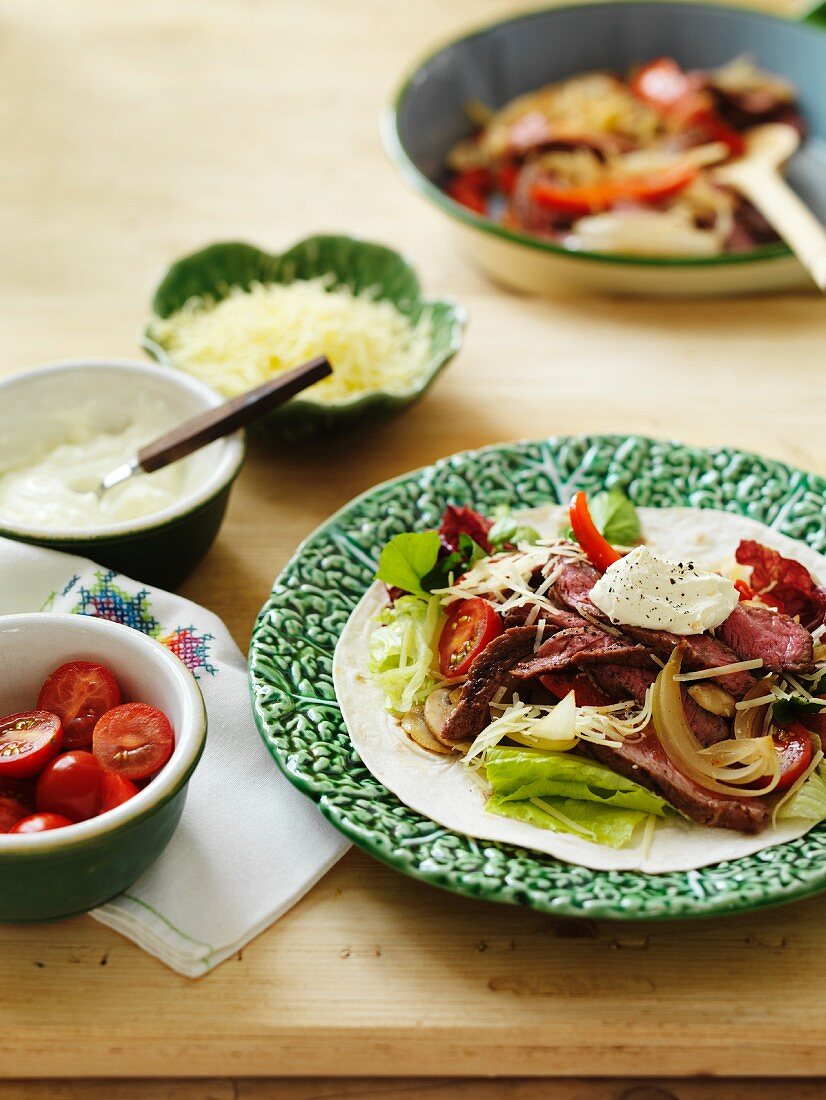 Beef fajitas with sour cream, tomatoes and cheese