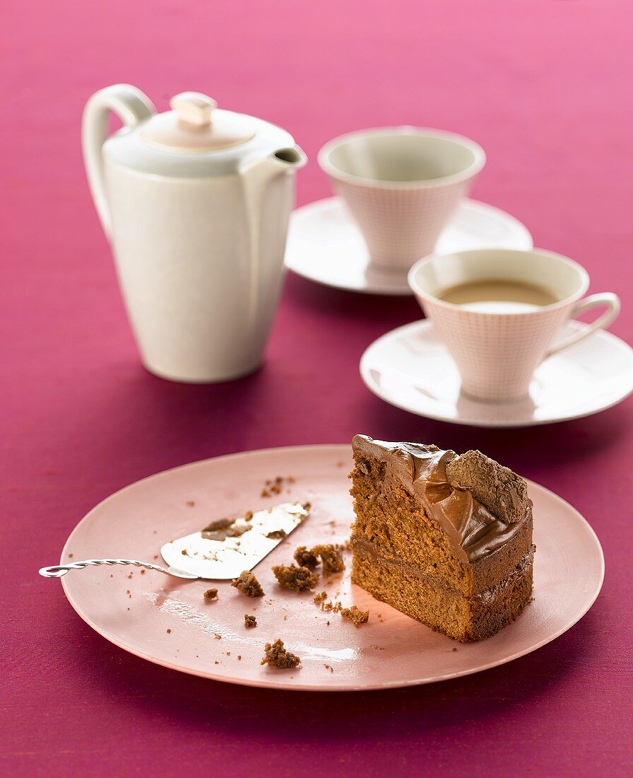 A slice of chocolate cake and cups of tea