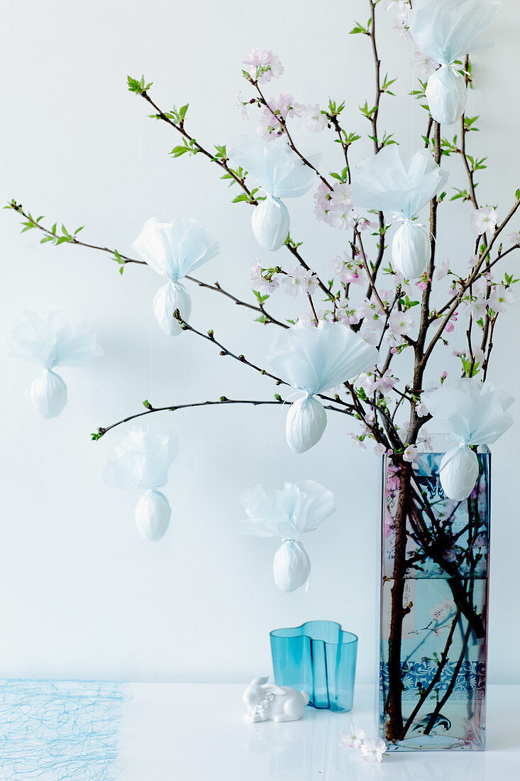 Easter eggs wrapped in napkins hanging from a cherry blossom sprig